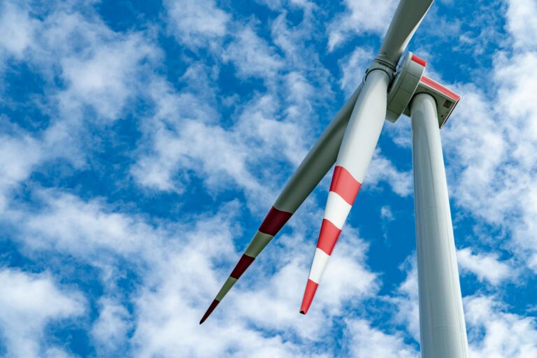 A striking wind turbine under a bright blue sky, symbolizing renewable energy and sustainability.